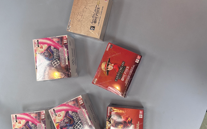 Sealed booster displays på lager hos BoosterBox: Gundam GD01 Newtype Rising, One Piece OP-13 og EB-02